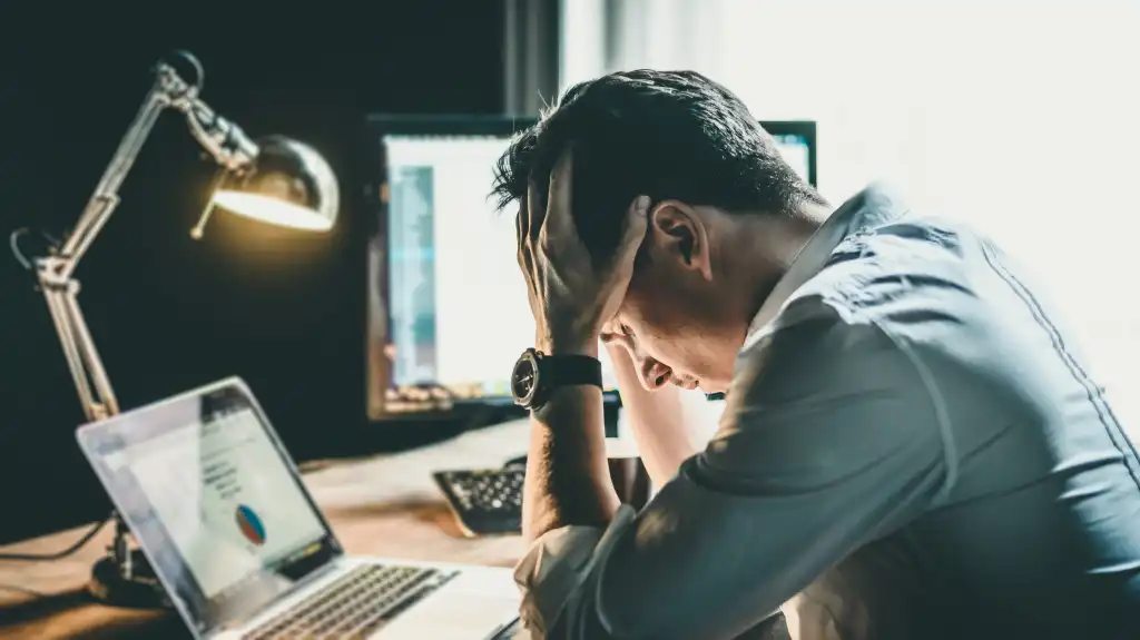 Tired and worried business man at workplace in office holding his head on hands after late night work, concept