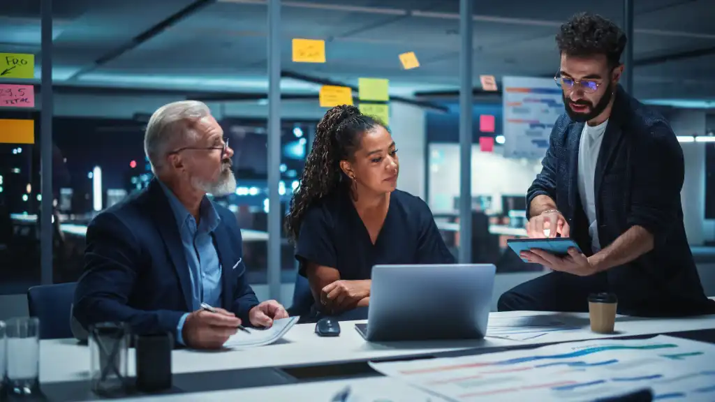 Office Conference Room Meeting: Diverse Team of Top Managers Talk, Brainstorm, Use Laptop Computer. Business Partners Discuss Financial Reports, Plan Investment Strategy and Managerial Operations.