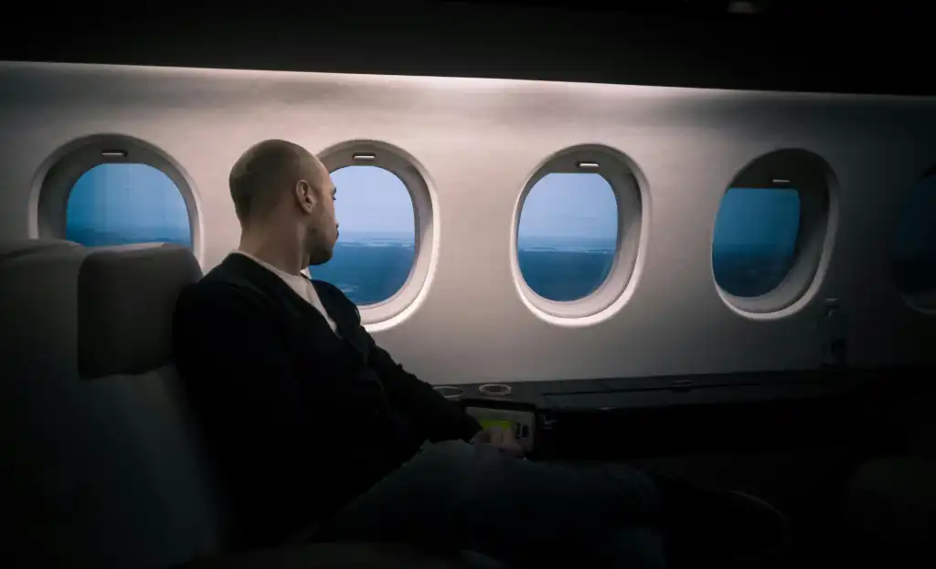 Man sitting near window in first class on an airplane.