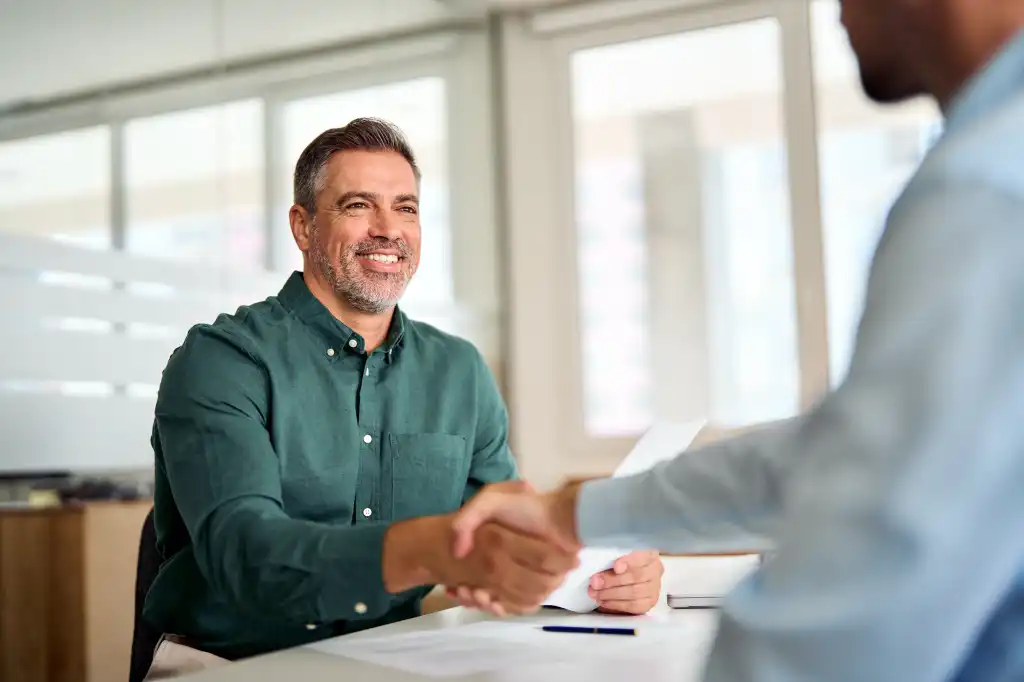 Smiling middle aged business man handshaking partner making partnership collaboration agreement at office meeting, hr manager and new worker shake hands recruiting at job interview. Welcome onboarding