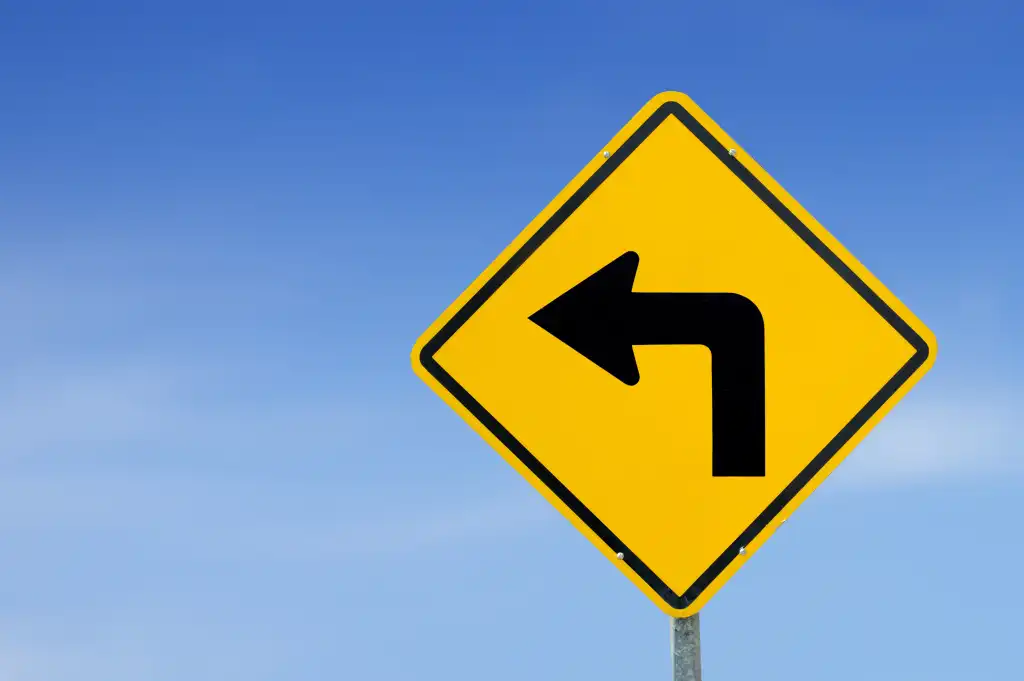 Left turn coming. Yellow traffic sign turn left against a blue sky background.