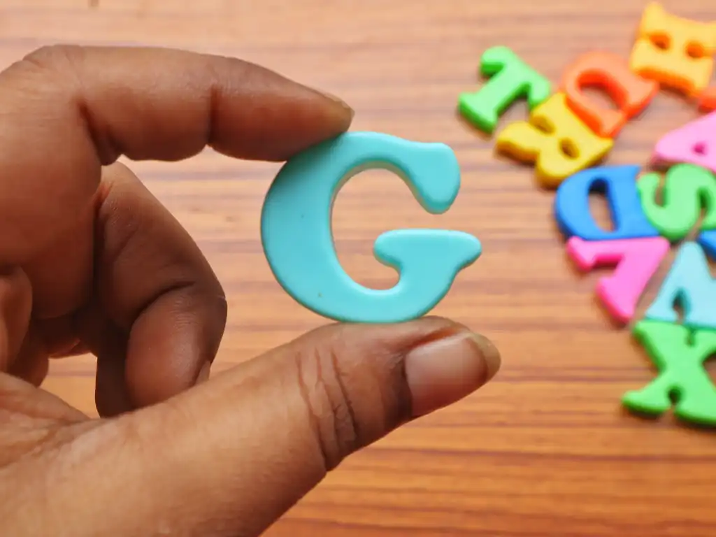 Closeup of a hand holding the English alphabet letter G.