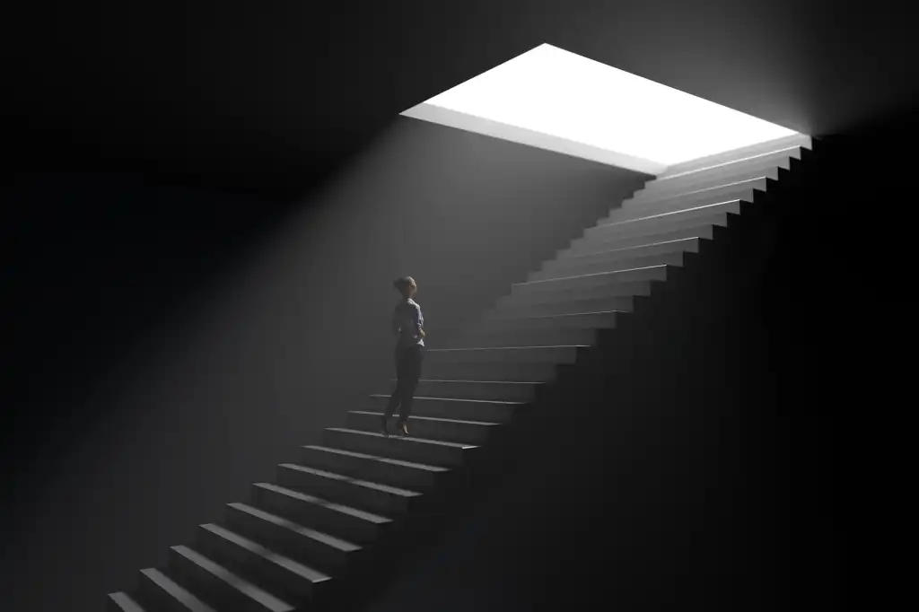 A woman climbs steps from darkness toward light.