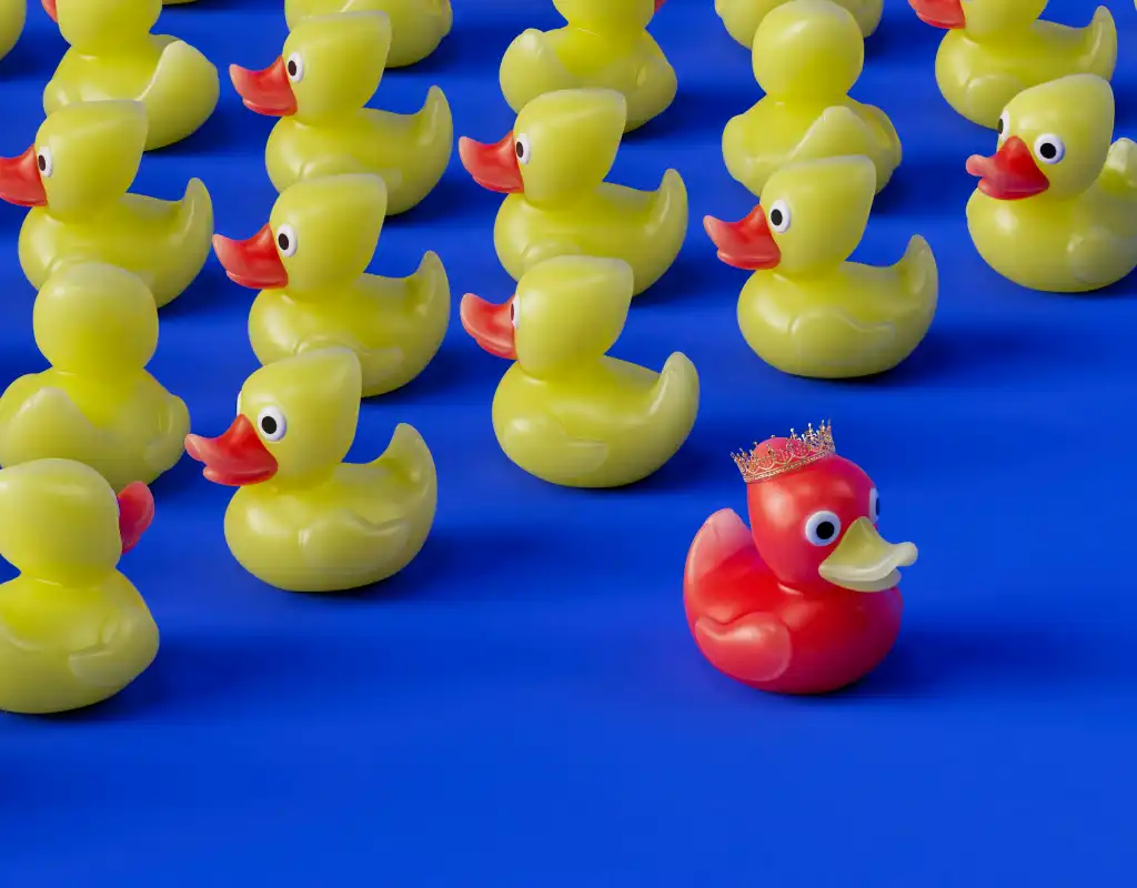 A group of yellow rubber ducks, and a red rubbe duck witha crown on its head.