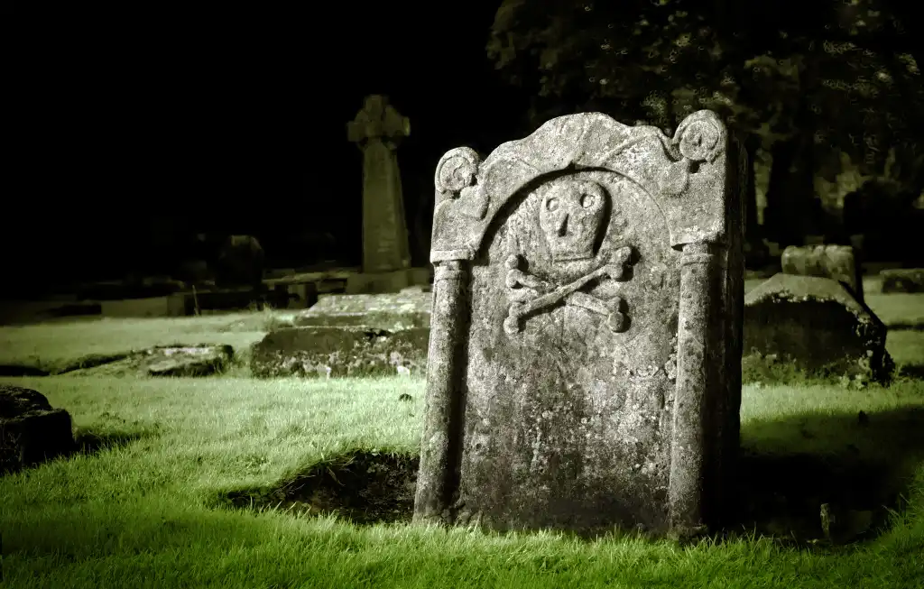 A gravestone with skull and bones