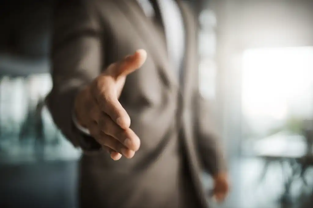 Closeup of professional executive businessman reaching for handshake to thank you for formal interview meeting. Corporate company manager hiring new employee in leadership development