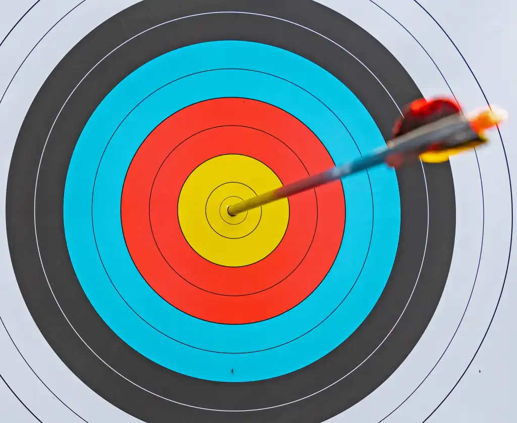 close-up view of archery target with yellow red blue black and white rings and arrow at the center - bullseye accuracy