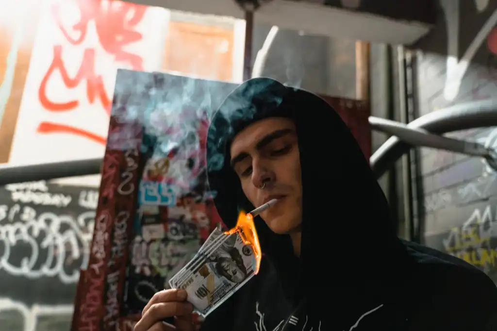 A man lights a cigarette with burning dollar bills.